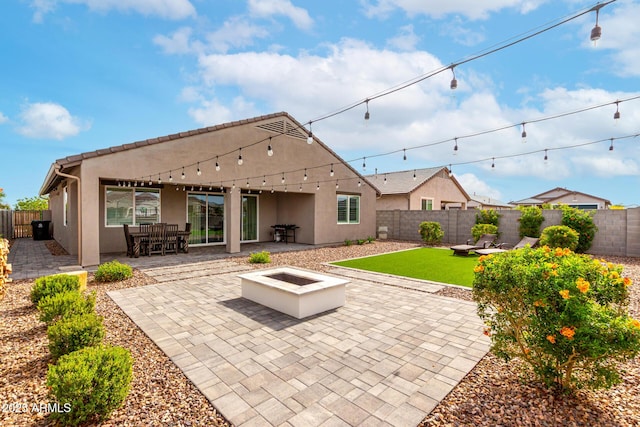 rear view of house with a fenced backyard, a patio area, stucco siding, and a fire pit