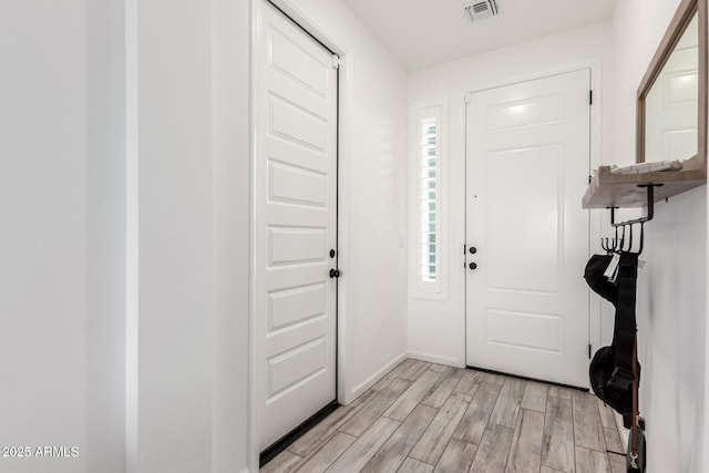 foyer entrance with light wood-style floors, baseboards, and visible vents