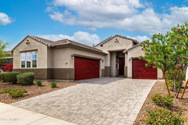 mediterranean / spanish-style house featuring a tile roof, an attached garage, driveway, and stucco siding