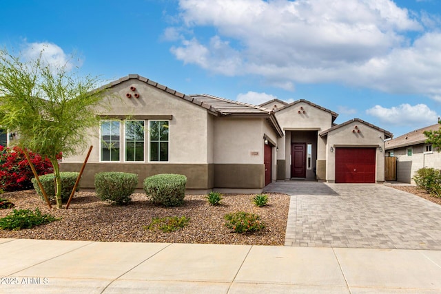 mediterranean / spanish home with fence, an attached garage, stucco siding, and decorative driveway