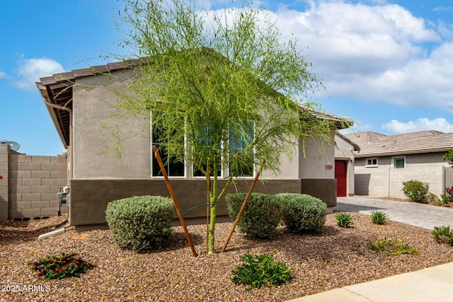 view of front of home with fence, stucco siding, an attached garage, and driveway