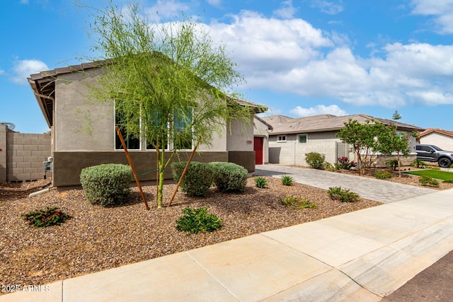 view of front facade with fence, a garage, driveway, and stucco siding