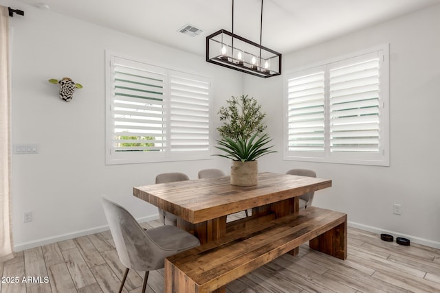 dining room with light wood-style floors, baseboards, visible vents, and an inviting chandelier