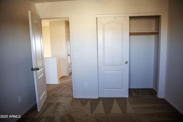 unfurnished bedroom featuring dark carpet and a closet