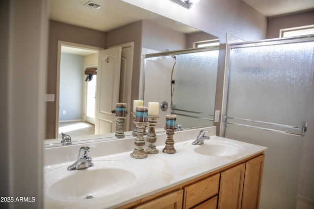 bathroom with a healthy amount of sunlight, a shower with shower door, and vanity