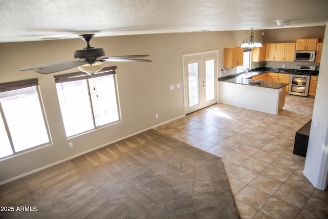 kitchen featuring appliances with stainless steel finishes, pendant lighting, light brown cabinetry, light colored carpet, and kitchen peninsula