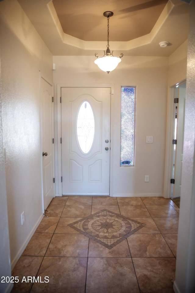 tiled foyer featuring a raised ceiling