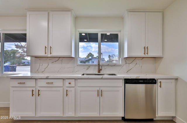 kitchen with light stone counters, dishwasher, sink, and white cabinets