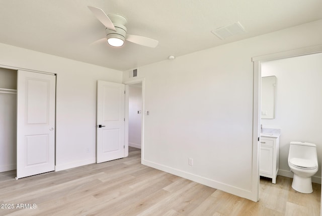 unfurnished bedroom featuring ceiling fan, connected bathroom, light wood-type flooring, and a closet