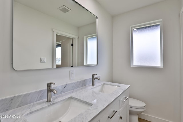 bathroom with a healthy amount of sunlight, toilet, and vanity