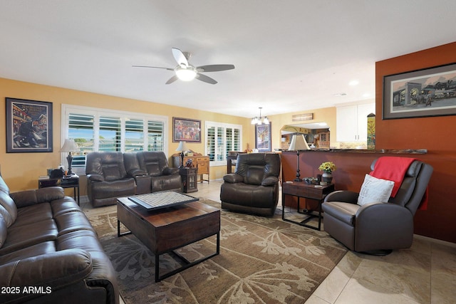 tiled living room with ceiling fan with notable chandelier