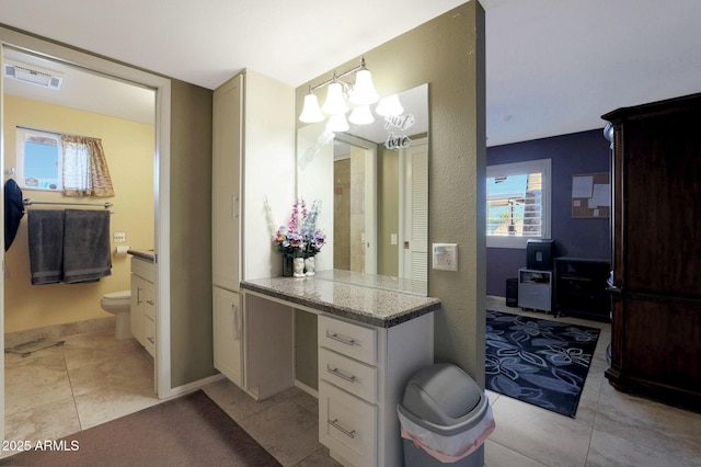 bathroom with toilet, a healthy amount of sunlight, tile patterned floors, and vanity