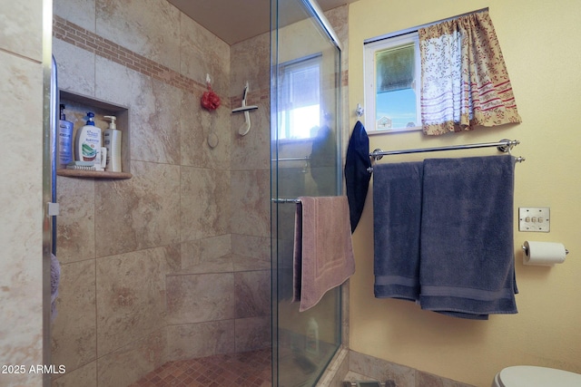 bathroom with toilet and a shower with door