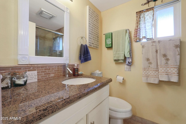 bathroom featuring decorative backsplash, toilet, vanity, and walk in shower