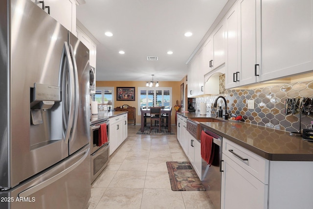 kitchen with white cabinetry, appliances with stainless steel finishes, decorative backsplash, hanging light fixtures, and sink