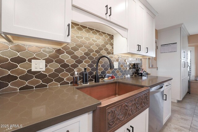 kitchen with stainless steel dishwasher, white cabinetry, sink, backsplash, and light tile patterned floors