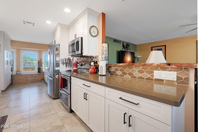 kitchen featuring kitchen peninsula, ceiling fan, appliances with stainless steel finishes, tasteful backsplash, and white cabinets