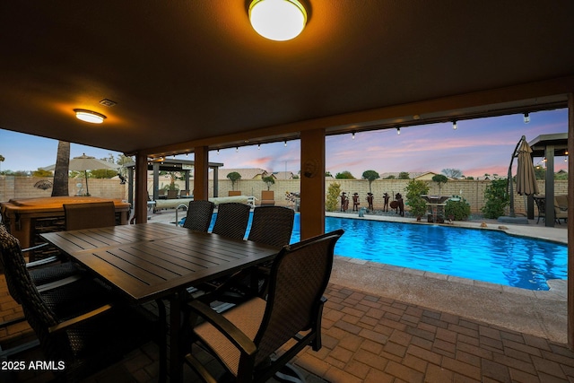 pool at dusk featuring a patio