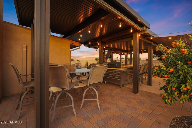 patio terrace at dusk with a bar and exterior kitchen