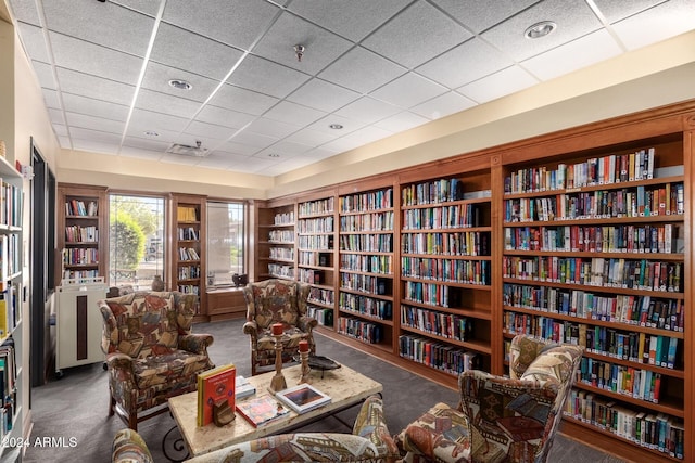 living area with a paneled ceiling and dark carpet