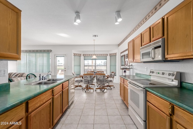 kitchen with light tile patterned flooring, white appliances, sink, and hanging light fixtures