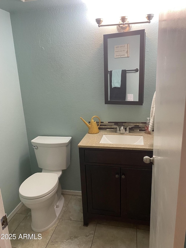 half bathroom with toilet, vanity, tile patterned flooring, and baseboards