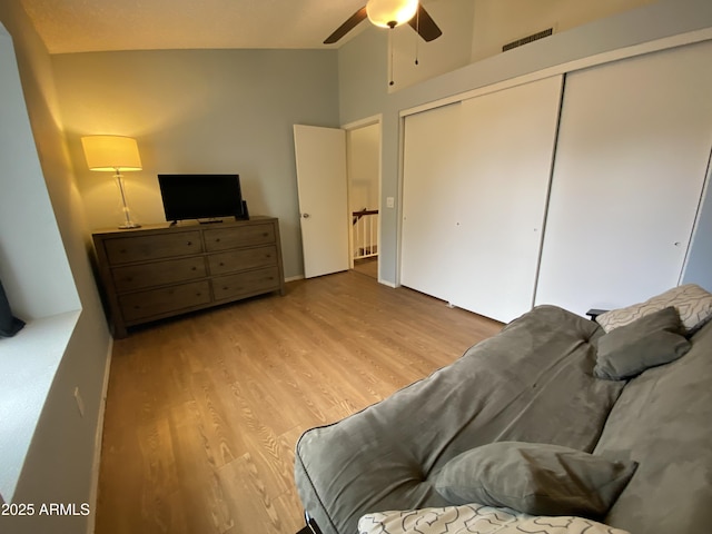 bedroom with wood finished floors, a closet, high vaulted ceiling, and a ceiling fan