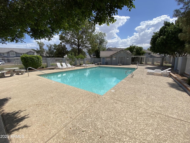 community pool with a patio area and fence