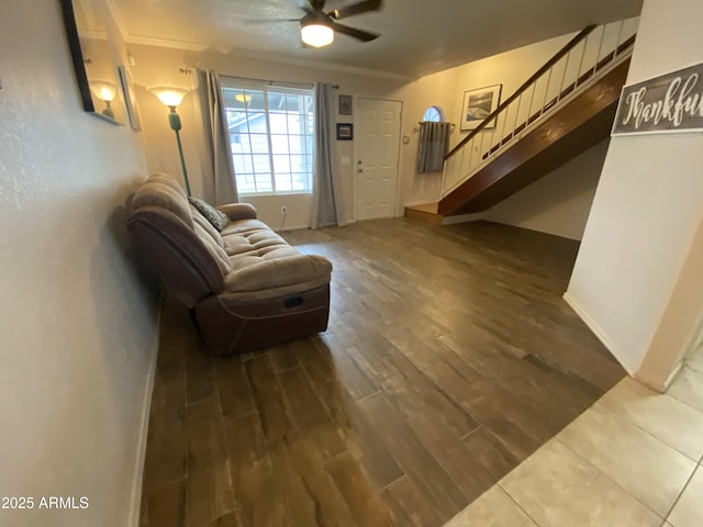 living area with a ceiling fan, stairs, dark wood finished floors, baseboards, and ornamental molding