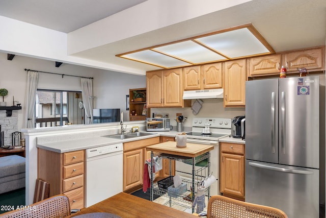 kitchen with light brown cabinets, kitchen peninsula, sink, and white appliances