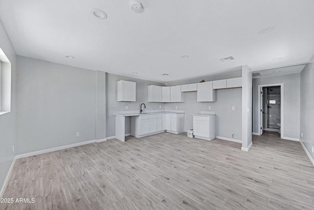 1804 E Pueblo Ave, Phoenix, AZ 85040 - kitchen featuring a sink, baseboards, white cabinets, light wood-style floors, and light countertops