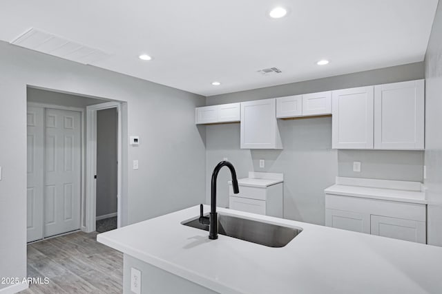 1804 E Pueblo Ave, Phoenix, AZ 85040 - kitchen featuring a sink, white cabinets, light wood-type flooring, recessed lighting, and light countertops