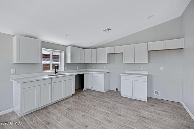 1804 E Pueblo Ave, Phoenix, AZ 85040 - kitchen with a sink, vaulted ceiling, white cabinets, light wood-style floors, and baseboards
