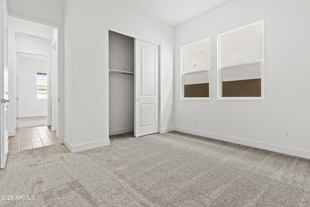 unfurnished bedroom featuring light colored carpet and a closet