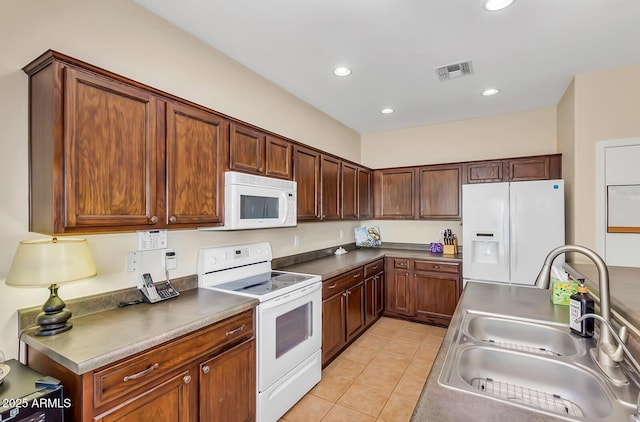 kitchen with white appliances, a sink, light tile patterned floors, recessed lighting, and dark countertops