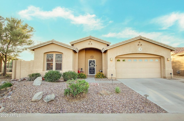 mediterranean / spanish-style house featuring stucco siding, a garage, driveway, fence, and a tiled roof