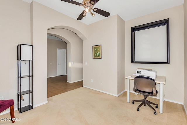 office featuring arched walkways, ceiling fan, carpet, and baseboards