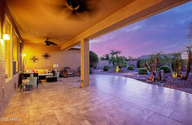 patio terrace at dusk featuring a ceiling fan, outdoor lounge area, and a fenced backyard