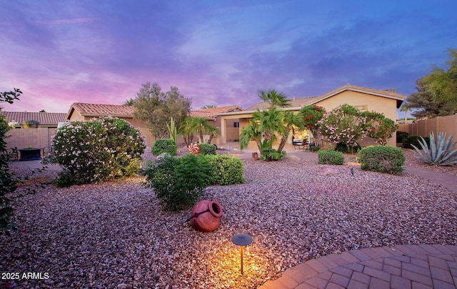 view of front of home with stucco siding, a patio, fence, and a tile roof
