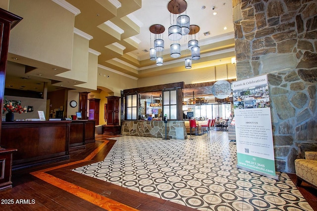 reception area with a towering ceiling, crown molding, arched walkways, ornate columns, and a chandelier