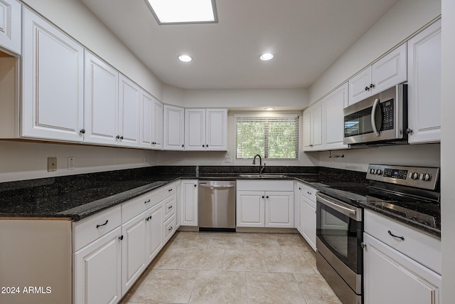 kitchen featuring stainless steel appliances, white cabinets, sink, and dark stone counters