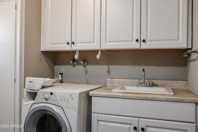 clothes washing area featuring washer / clothes dryer, cabinets, and sink