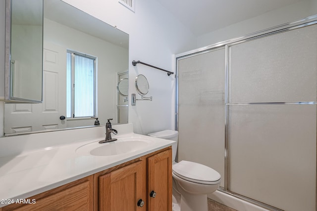 bathroom featuring vanity, toilet, and a shower with door