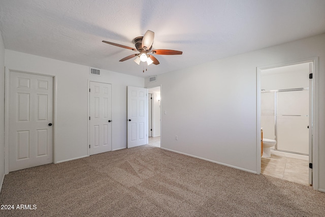 unfurnished bedroom with a textured ceiling, light colored carpet, ceiling fan, and ensuite bath