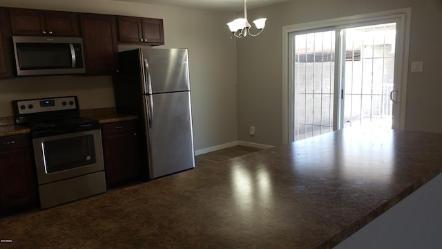 kitchen with stainless steel appliances, a chandelier, baseboards, pendant lighting, and dark countertops