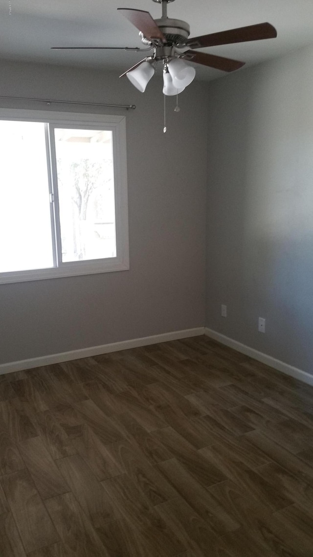 unfurnished room featuring dark wood-type flooring, ceiling fan, and baseboards