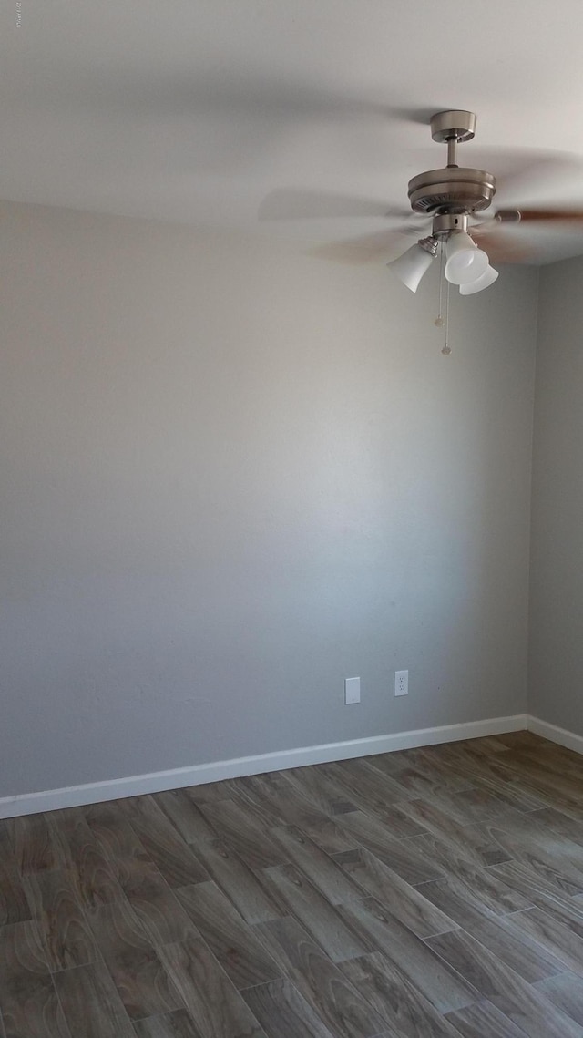 spare room featuring a ceiling fan, dark wood-type flooring, and baseboards