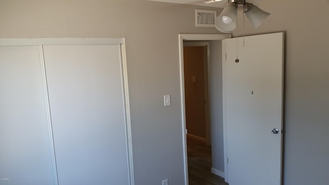 unfurnished bedroom featuring a closet, dark wood-style floors, and ceiling fan