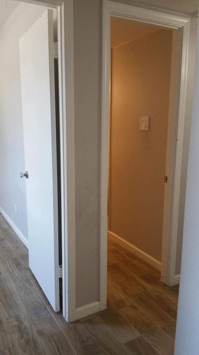 corridor featuring baseboards and wood finished floors