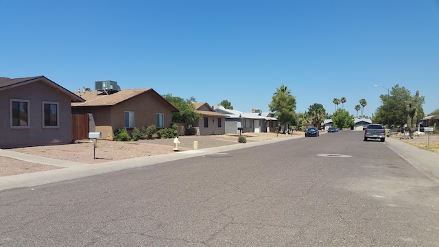 view of asphalt road with street lighting, a residential view, curbs, and sidewalks